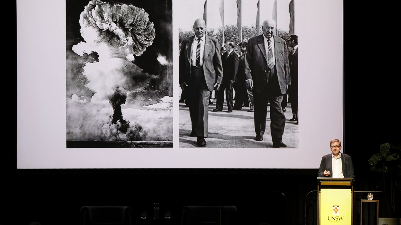 Serhii Plokhy on stage in front of an image of the historic Chernobyl diaster