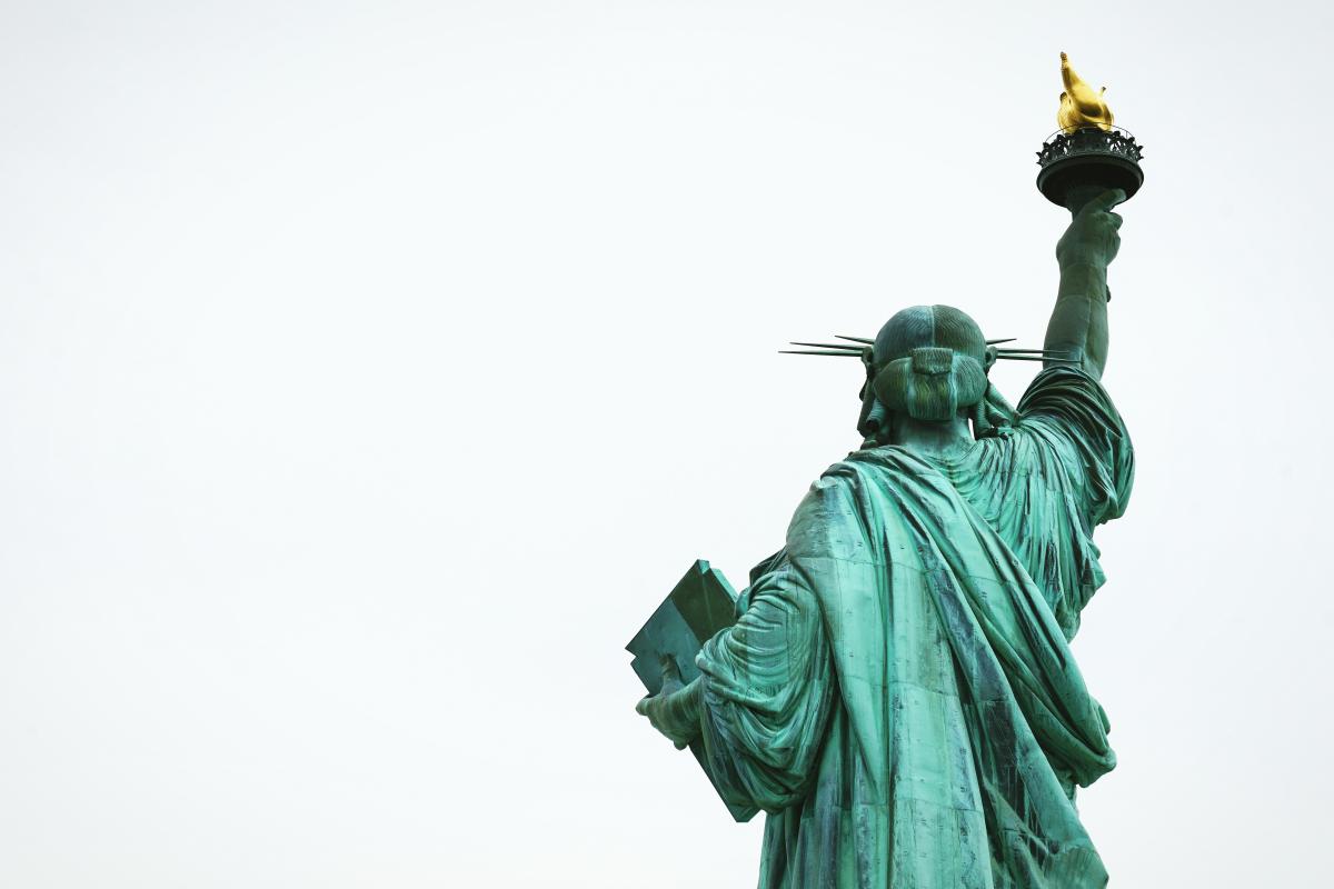Statue of Liberty viewed from behind looking out to a grey cloudy sky