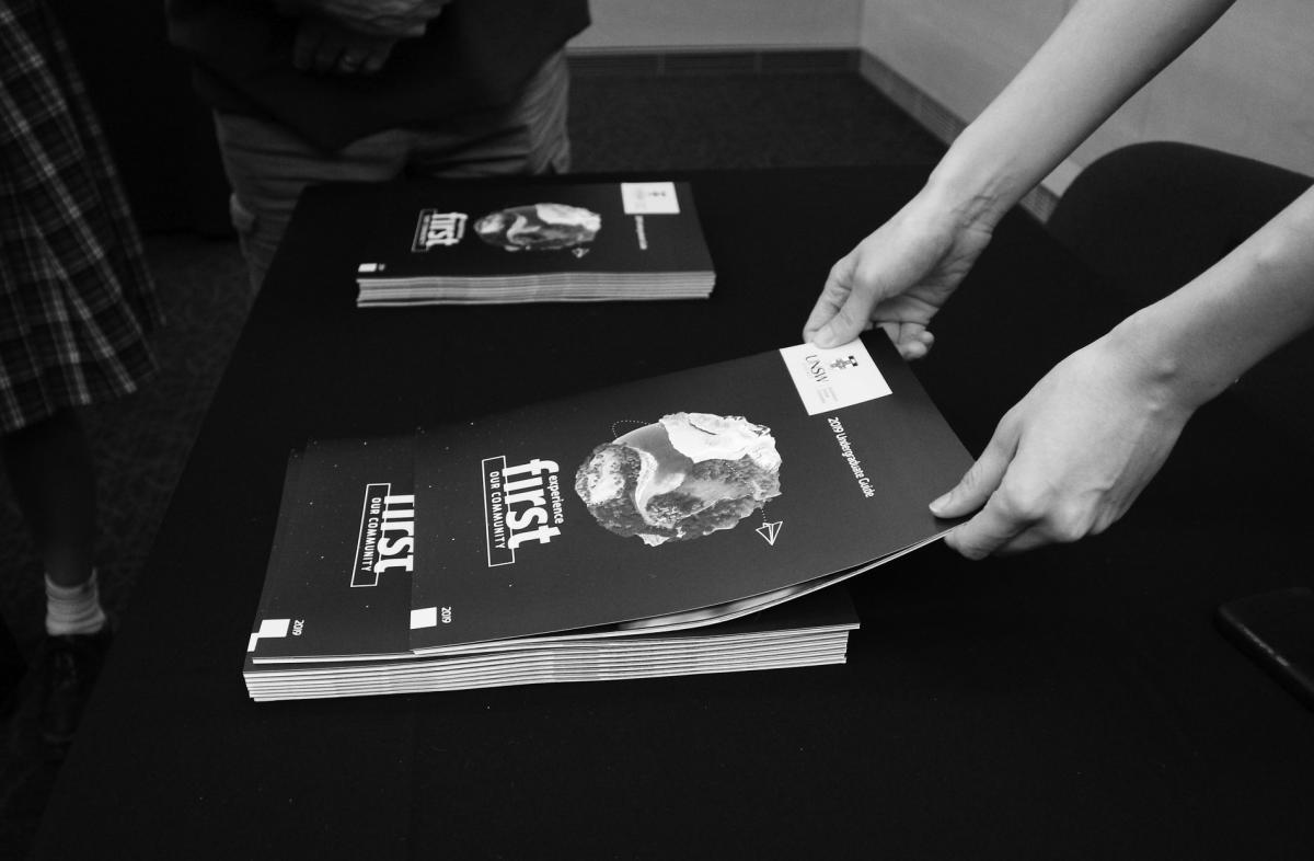photo hands picking up brochure on black table