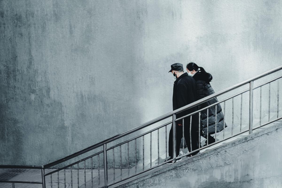 artistic photo of two people wearing face masks walking down stairs