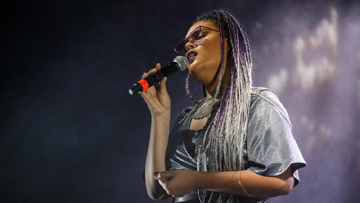 Performer Mi-kaisha singing, with a microphone in one hand. 